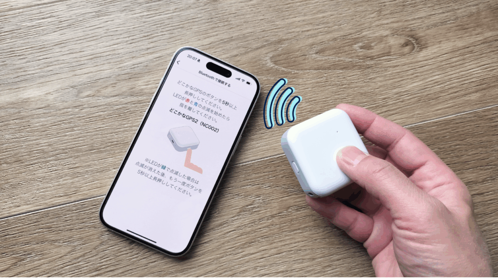 みまもりGPS本体とスマホを近づけ、Bluetoothで設定を行っている様子の写真。