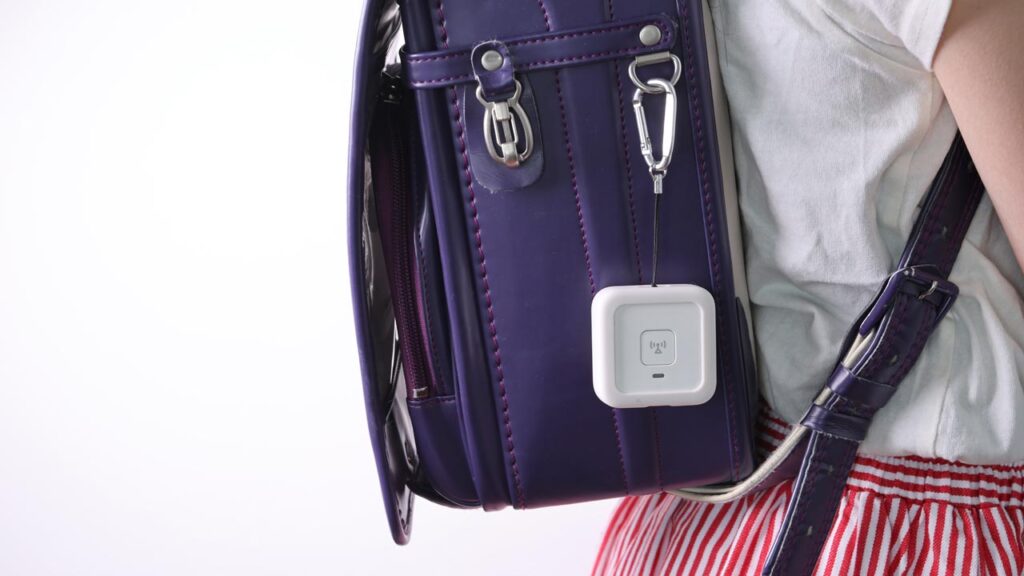 ランドセルのサイドポに子ども用GPS端末を
ストラップで固定している様子の写真。