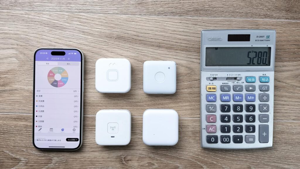 子どもGPS端末と電卓、家計簿アプリの画面を並べた写真。子どもGPSの料金を比較しながら検討しているイメージ。

